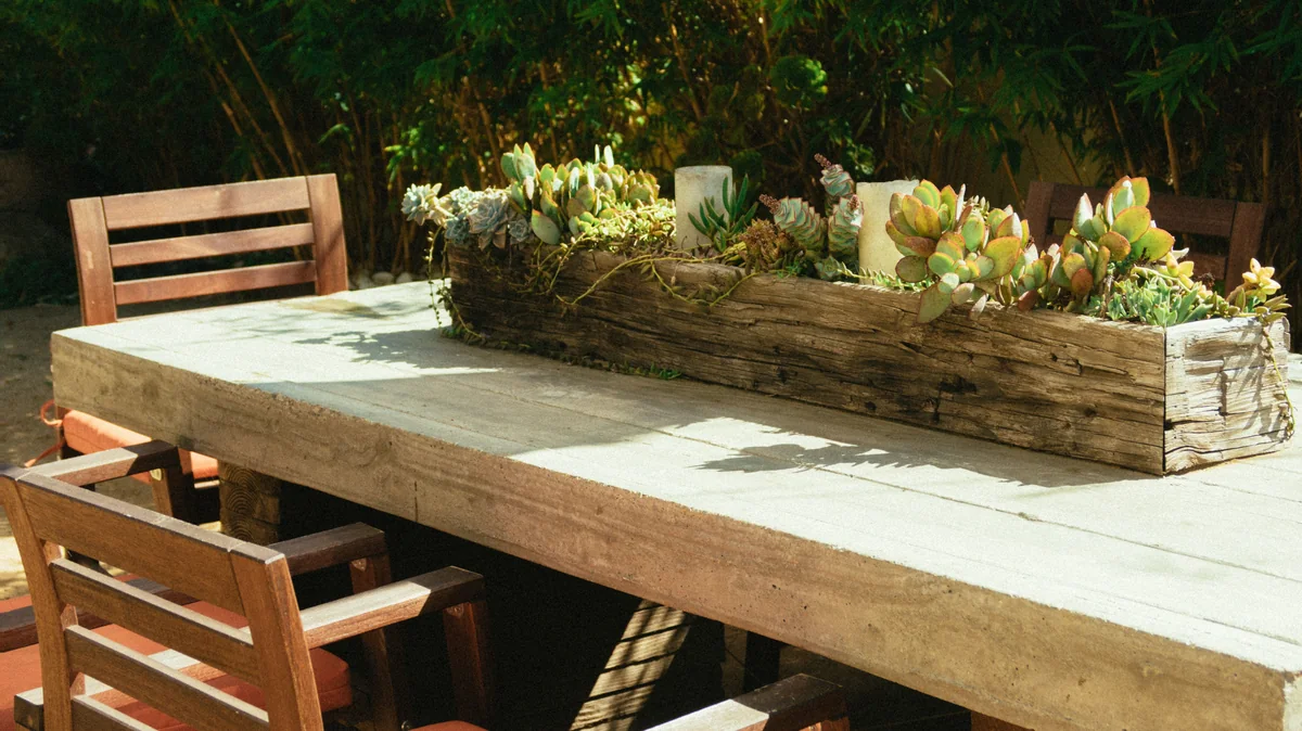 Long rectangular wooden planter filled with succulents on a patio table